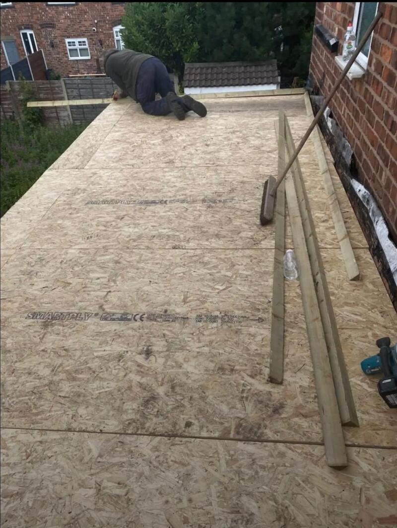 One of the team fixing new deck boards on a flat roof